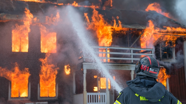 firefighter putting out house fire with hose